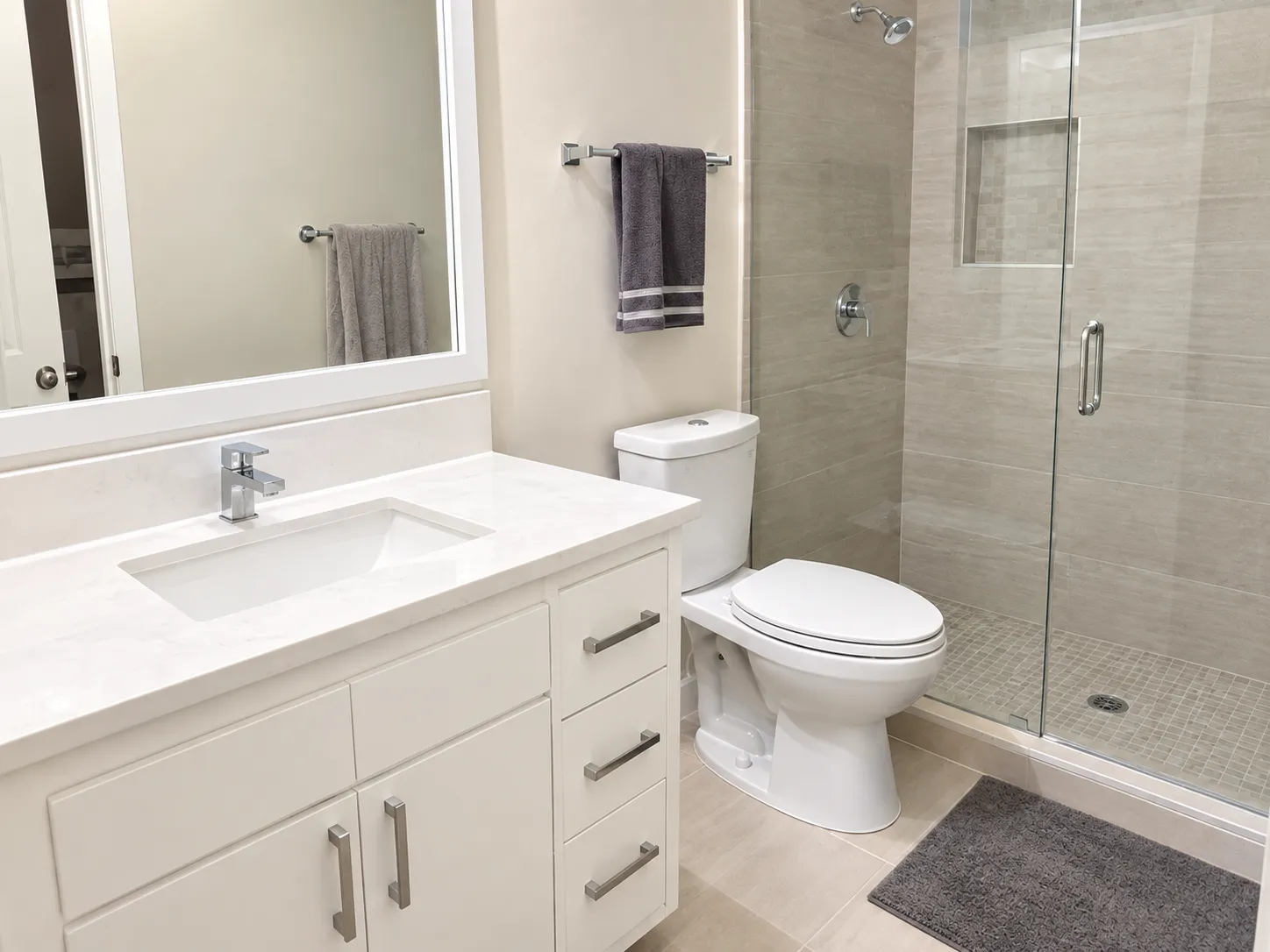 Bright bathroom with a white vanity and glass shower after decluttering, with clear countertops